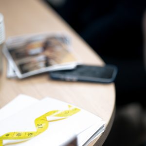 Carnet avec un mètre ruban posé sur une table lors d’un atelier collectif au Centre Phœnix Grenoble, symbolisant le suivi du poids et de l’obésité