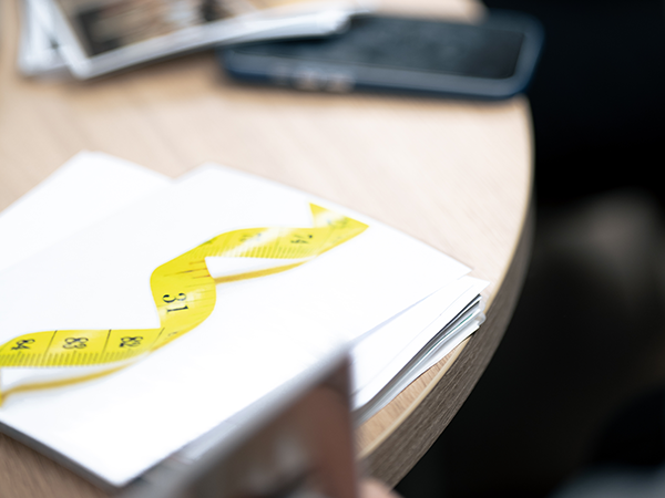 Carnet avec un mètre ruban jaune, symbole de la prise en charge de l’obésité et du surpoids.